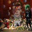 A fan poses in front of the mural of late British pop icon David Bowie created by Australian street artist James Cochran, as fans payed their respects in Brixton, south London on January 10, 2017, on the first anniversary of Bowie's death