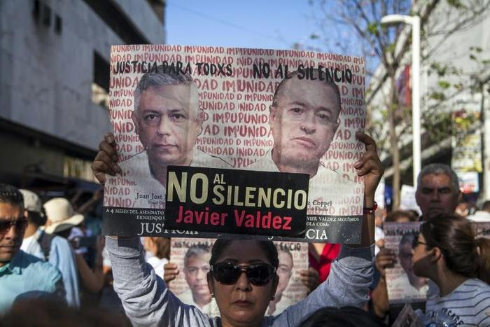 A woman holds a sign reading, "Justice for all. No to silence" as journalists, friends and relatives pay tribute to slain Mexican journalist Javier Valdez in May 2018