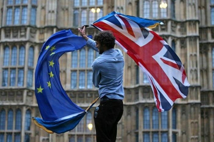 A man waves both a Union flag and a European flag outside the Houses of Parliament at an anti-Brexit protest in central London on June 28, 2016shortly after the referendum ended with a British vote to leave the EU