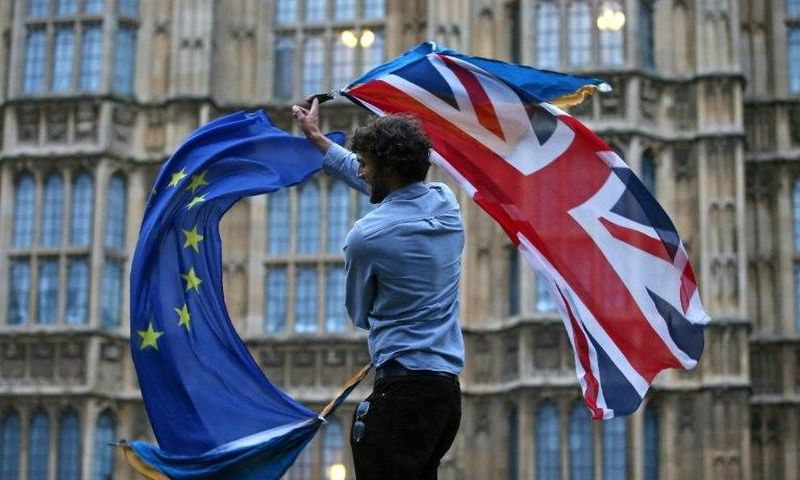 A man waves both a Union flag and a European flag outside the Houses of Parliament at an anti-Brexit protest in central London on June 28, 2016shortly after the referendum ended with a British vote to leave the EU