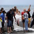 Police, firefighters and onlookers stand by the covered body of a bodyboarder killed by a shark on a beach in Saint-Andre, on the French Reunion Island in the Indian Ocean on February 21, 2017