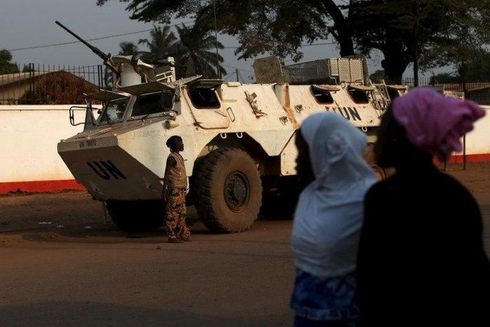 Women walk by a United Nations peacekeeping armoured vehicle guarding the outer perimeter of a compound of a school used as an electoral centre at the end of the presidential and legislative elections, in the mostly muslim PK5 neighbourhood of Bangui, ...