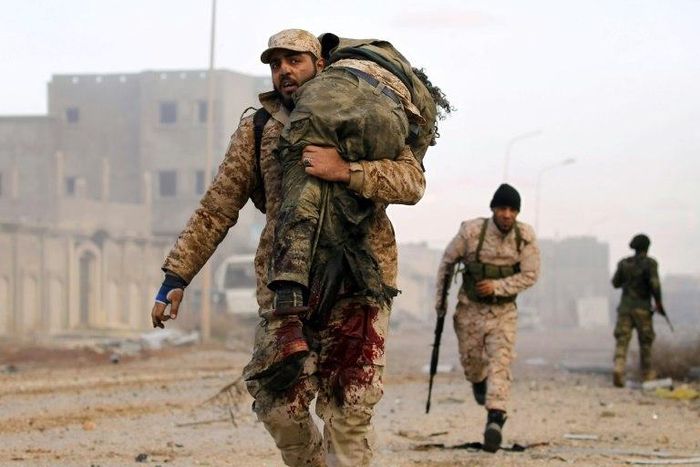 A member of the Libyan National Army (LNA) carries an injured comrade during fighting against jihadists in Qanfudah, on the southern outskirts of Benghazi