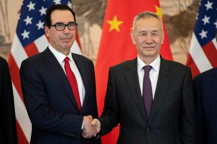 China's Vice Premier Liu He (R) shakes hands with US Treasury Secretary Steven Mnuchin (L) as they pose for a group photo at the Diaoyutai State Guesthouse in Beijing