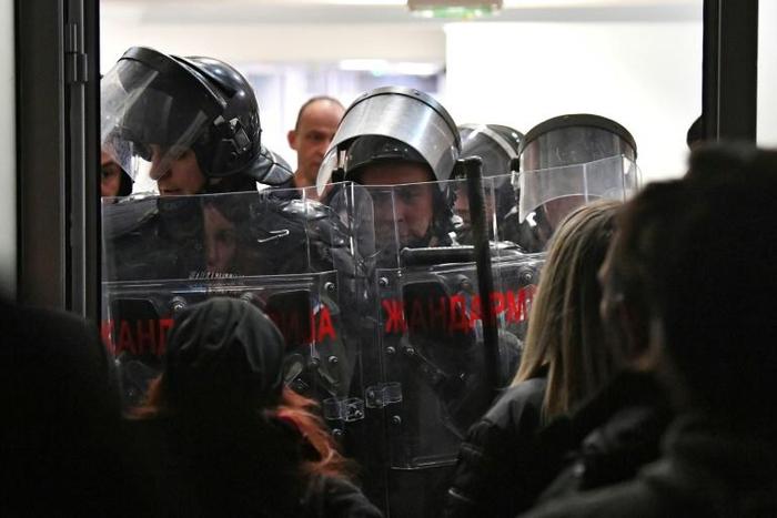 Police stand guard after protestors burst into state-run RTS televsion