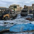 A picture taken with a mobile phone on February 16, 2017 shows burnt vehicles at the scene of a massive car bomb which killed dozens in a used car market in southern Baghdad