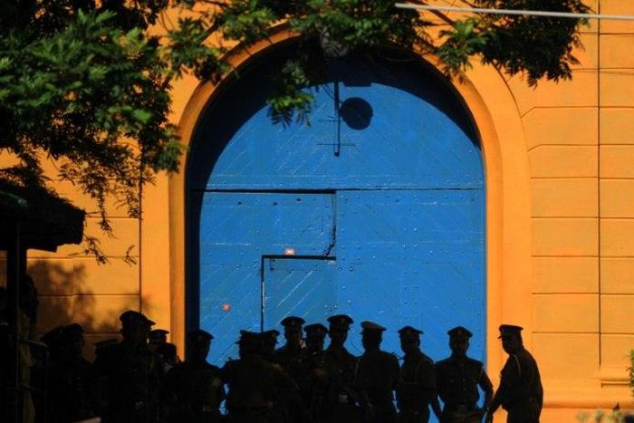 Sri Lankan policemen stand guard in front of protesters outside the main prison in Colombo on August 8, 2011