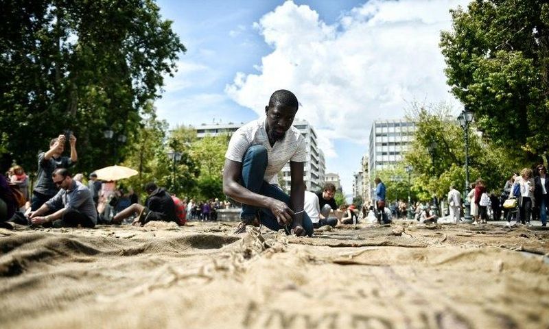 Ghanian artist Ibrahim Mahama performs "Check Point - Prosfygika" on the main Syntagma square in Athens on April 7, 2017 on the eve of the opening of the 14th edition of the Documenta 14 art exhibition