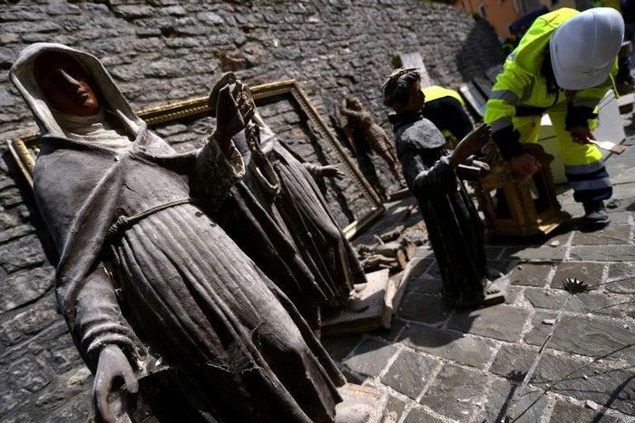 A volunteer on the "blue helmet" brigade to rescue historic artwork cleans statues recovered from the San Francesco di Visso