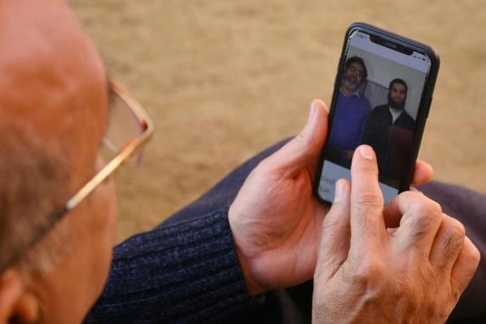 A relative looks at a picture on a mobile phone of Pakistani nationals Naeem Rashid and his son Talha Naeem, who were killed in the attacks to the Christchurch mosques in New Zealand
