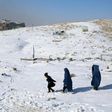 Burqa-clad women walk with a child through the snow in Ghazni province, southern Afghanistan on January 16, 2017