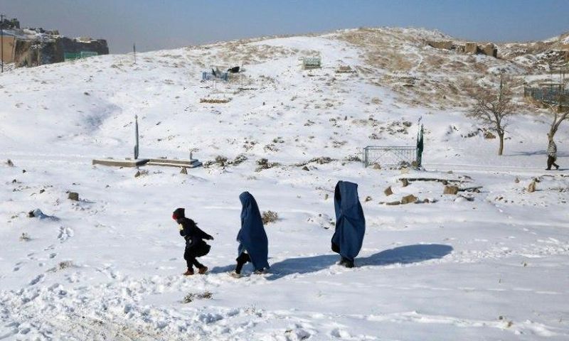 Burqa-clad women walk with a child through the snow in Ghazni province, southern Afghanistan on January 16, 2017