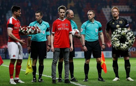 John Palmer (C), brother of Charlton Athletic season ticket holder, PC Keith Palmer, who was killed in the March 22, 2017 Westminster terror attack, greets match officials and players at The Valley Stadium in London