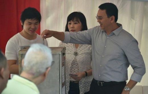 Incumbent Jakarta governor Basuki Tjahaja Purnama casts his ballot next to his wife Veronica and son Nicholas at a polling station on April 19, 2017