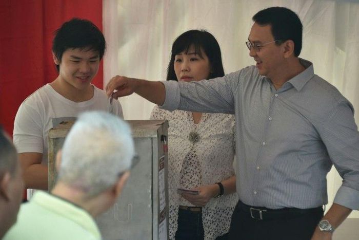 Incumbent Jakarta governor Basuki Tjahaja Purnama casts his ballot next to his wife Veronica and son Nicholas at a polling station on April 19, 2017