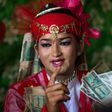 A medium wearing a red outfit and heavy make-up prepares to dance in honour of Myanmar's spirit guardian of drunkards and gamblers