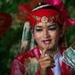 A medium wearing a red outfit and heavy make-up prepares to dance in honour of Myanmar's spirit guardian of drunkards and gamblers