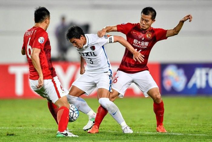 Shoji Gen (centre) of Japan's Kashima Antlers fights for the ball with Huang Bowen of China's Guangzhou Evergrande during their AFC Champions League match in Guangzhou, in China's Guangdong province on May 23, 2017