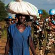 A displaced woman carries goods as UN peacekeepers patrol outside UN Protection of Civilians premises in Juba