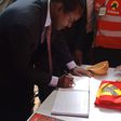 Wiper party leader Kalonzo Musyoka signs the visitor's book at a Jubilee party stand during the  People's Democratic Festival (Twitter)