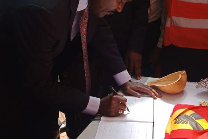 Wiper party leader Kalonzo Musyoka signs the visitor's book at a Jubilee party stand during the  People's Democratic Festival (Twitter)