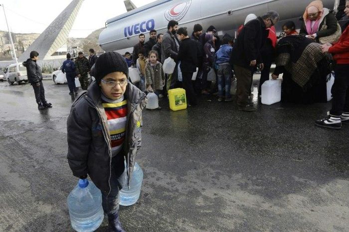 Syrians wait to fill plastic containers with water provided by the Syrian Arab Red Crescent in the capital Damascus on January 10, 2017