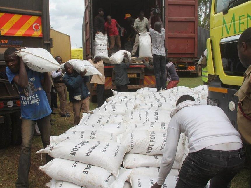 Suspected contraband sugar being offloaded from trucks after police impounded a truck full of them