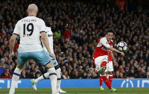 Arsenal's midfielder Mesut Ozil (R) shoots to score the opening goal of the English Premier League football match between Arsenal and West Ham United at the Emirates Stadium in London on April 5, 2017