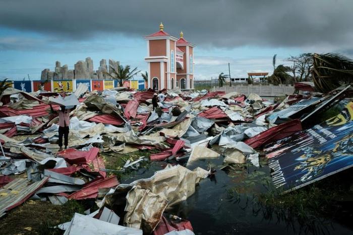 People collect metal sheets from a damaged supermarket to rebuild their houses destroyed by Cyclone Idai in Beira, Mozambique