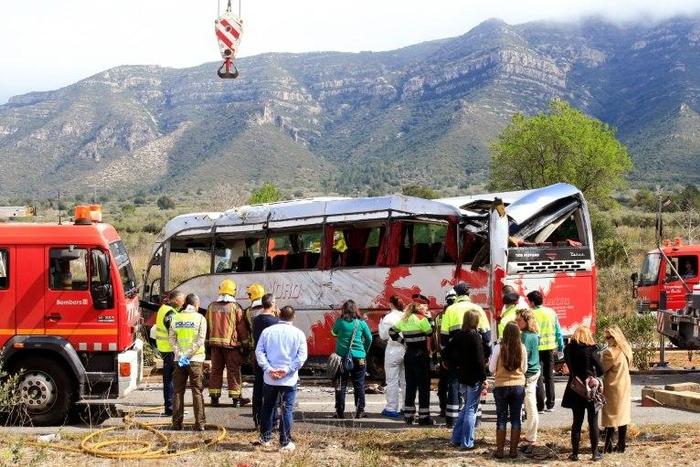 Emergency personnel stand before the righted bus on the Spanish AP-7 motorway following a fatal accident that claimed the lives of 13 foreign students an injured 44 others on March 20, 2016