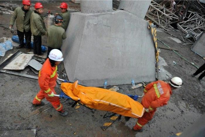 Workers carry a body on a stretcher from the remains of a collapsed platform in a cooling tower at a power station at Fengcheng in China's Jiangxi province on November 24, 2016