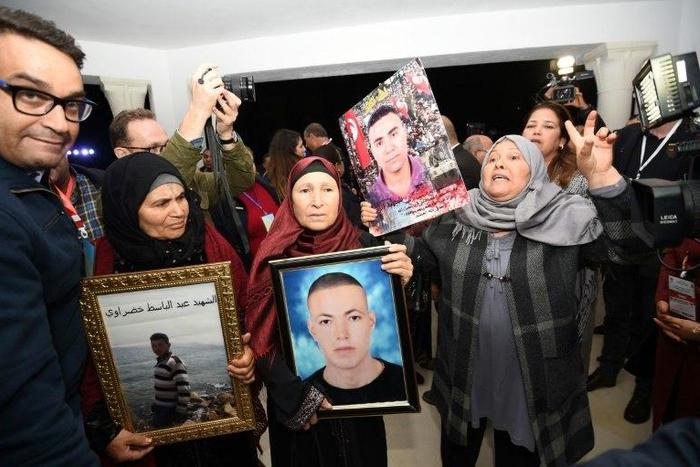 Tunisian mothers of torture victims carry their sons' portraits at the The Truth and Dignity Commission in Tunis