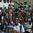 Gambians celebrate in front of an Economic Community of West African States armoured vehicle outside of the Statehouse in Banjul on January 23, 2017