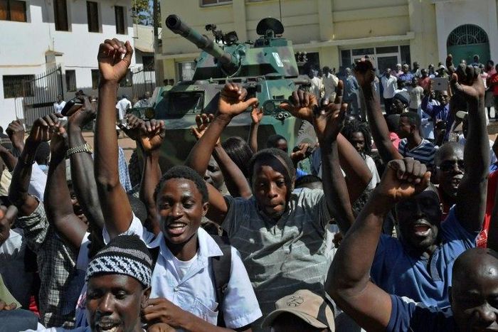 Gambians celebrate in front of an Economic Community of West African States armoured vehicle outside of the Statehouse in Banjul on January 23, 2017