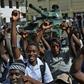 Gambians celebrate in front of an Economic Community of West African States armoured vehicle outside of the Statehouse in Banjul on January 23, 2017