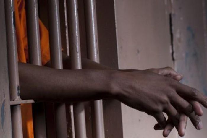 Hands gripping the bars of a jail cell