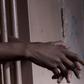Hands gripping the bars of a jail cell