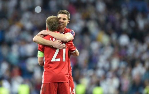 Bayern Munich's defender Philipp Lahm (L) hugs teammate Xabi Alonso (R) after their UEFA Champions League quarter-final second leg football match against Real Madrid at the Santiago Bernabeu stadium in Madrid on April 18, 2017