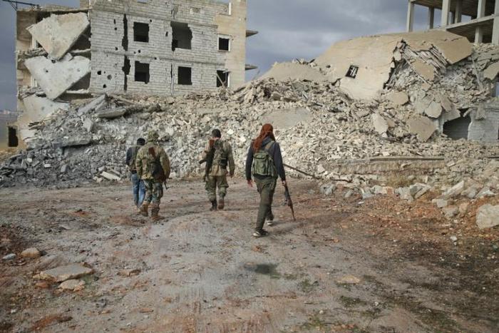Syrian rebels from the National Liberation Front (NLF)walk through the Aleppo province's al-Rashidin district on November 26, 2018