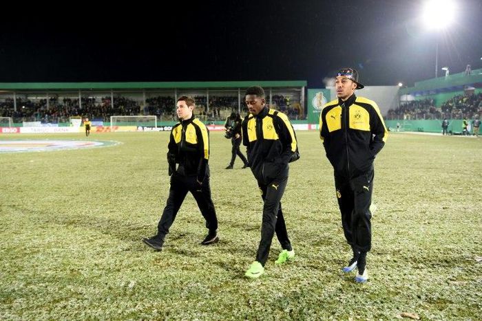 Dortmund's (from L) Raphael Guerreiro, Ousmane Dembele and Pierre-Emerick Aubameyang walk accross the pitch after their cancelled German Cup match against Sportfreunde Lotte due to heavy snowfall, in Lotte, on February 28, 2017