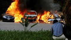A photographer capturing images of cars burning after they were bombed at Dusit complex