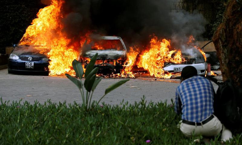 A photographer capturing images of cars burning after they were bombed at Dusit complex
