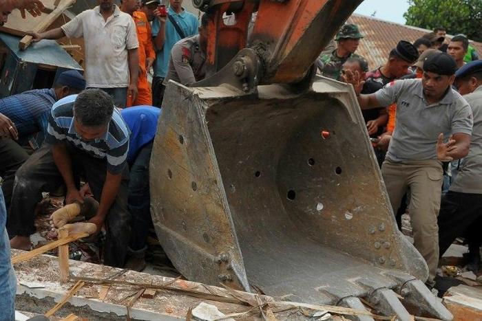 Residents rescue an earthquake survivor from rubble in Pidie Jaya, Indonesia's Aceh province, on December 7, 2016