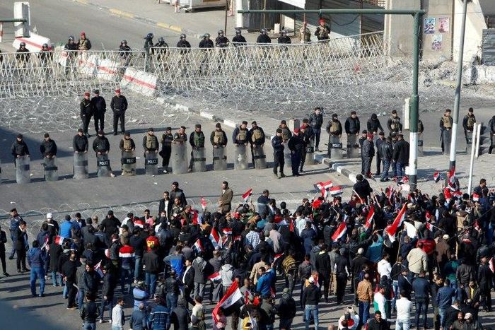 Iraqi security forces stand guard as supporters of the Sadrist movement gather during a demonstration in Baghdad's Tahrir Square on February 11, 2017, to demand the formation of an independent electoral commission