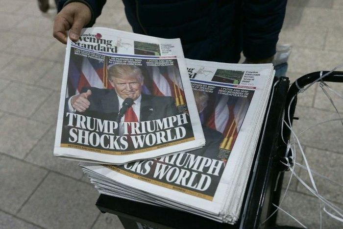 Commuters take copies of the Evening Standard Newspaper in central London on November 9, 2016