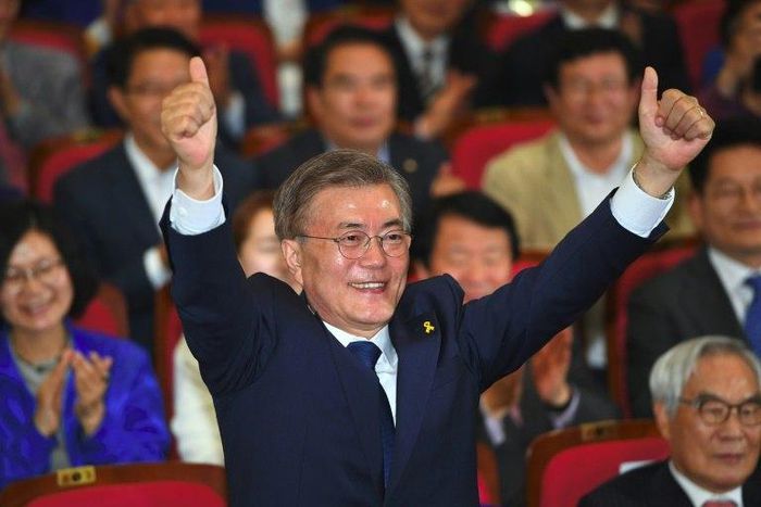 South Korean presidential candidate Moon Jae-in (C) gives the thumbs-up as he watches screens showing the result of exit polls of the presidential election at a hall of the National Assembly in Seoul on May 9, 2017
