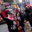 Syrian and Iraqi refugee families take selfies in Times Square during a tour of Manhattan in New York