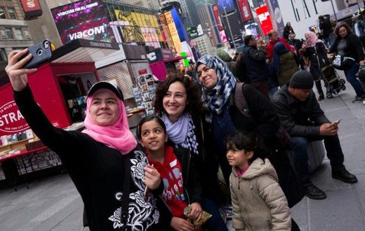 Syrian and Iraqi refugee families take selfies in Times Square during a tour of Manhattan in New York