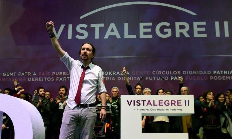 Pablo Iglesias (L), leader of left-wing party Podemos, raises his fist during the second day of the party congress at Vistalegre bullring in Madrid on February 12, 2017 that saw him re-elected as general secretary