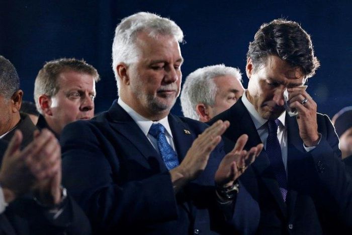 Canada's Prime Minister Justin Trudeau (R) wipes a tear as he stands beside Quebec Premier Philippe Couillard during funeral services for three of the victims of the deadly shooting at the Quebec Islamic Cultural Centre, in Montreal, February 2, 2017